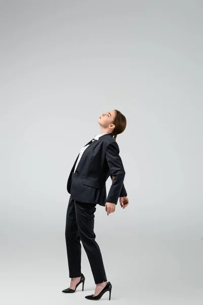 Side view of businesswoman marionette in suit posing isolated on grey — Stock Photo