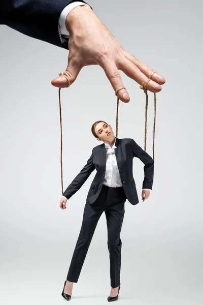 Cropped view of puppeteer holding businesswoman marionette on strings isolated on grey — Stock Photo