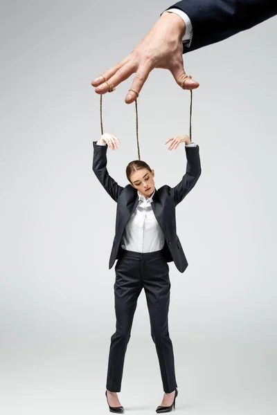 Cropped view of puppeteer holding businesswoman marionette on strings isolated on grey — Stock Photo