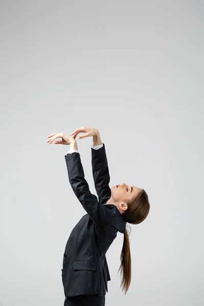 Вид сбоку на предпринимательницу-марионетку в костюме, позирующую изолированной на сером — стоковое фото