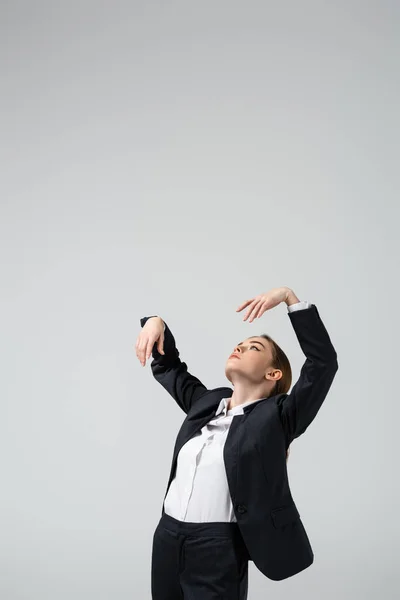 Mujer de negocios marioneta en traje posando con las manos levantadas aisladas en gris - foto de stock