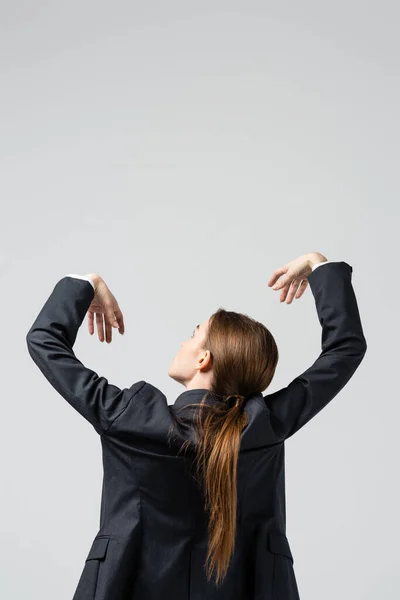 Вид деловой женщины-марионетки в костюме, позирующей с поднятыми руками, изолированной на сером — стоковое фото