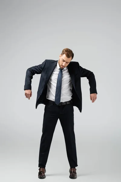 Hombre de negocios marioneta en traje posando con las manos abajo aislado en gris - foto de stock