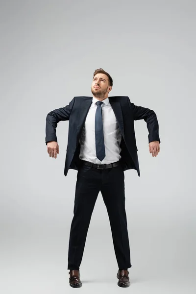 Hombre de negocios marioneta en traje posando con las manos abajo aislado en gris - foto de stock