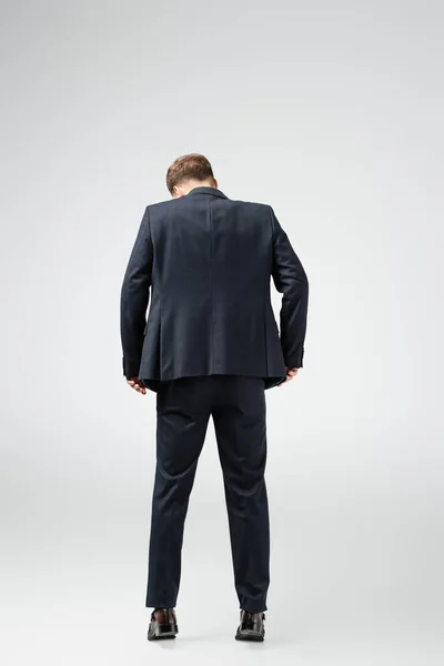 Vista trasera de la marioneta de hombre de negocios en traje aislado en gris - foto de stock