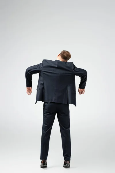 Vista posterior de la marioneta de hombre de negocios en traje posando con las manos abajo aislado en gris - foto de stock