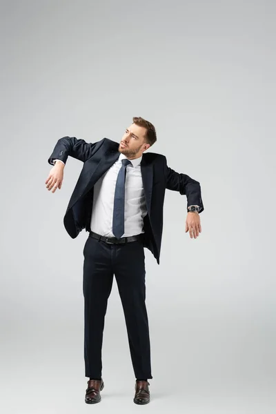 Hombre de negocios marioneta en traje posando con las manos abajo aislado en gris - foto de stock