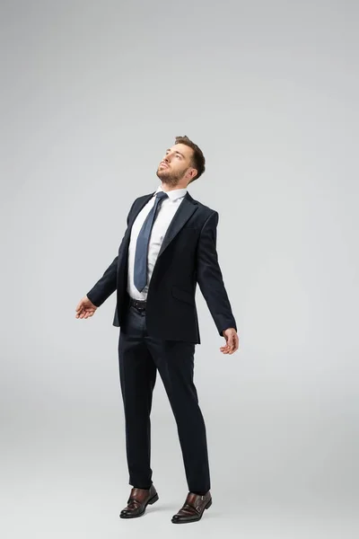 Hombre de negocios marioneta en traje posando con las manos abajo aislado en gris - foto de stock