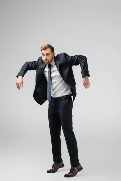 Uomo d'affari marionetta in giacca e cravatta posa con le mani in giù isolato su grigio — Foto stock