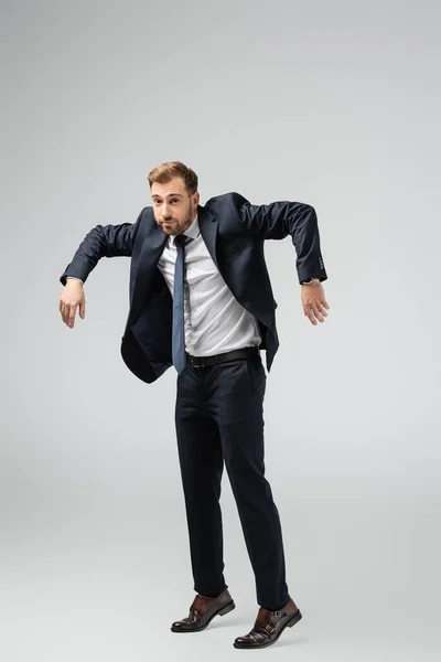 Businessman marionette in suit posing with hands down isolated on grey — Stock Photo