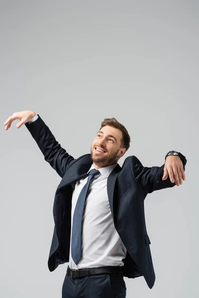 Щасливий бізнесмен маріонетка в костюмі позує з піднятими руками ізольовані на сірому — стокове фото