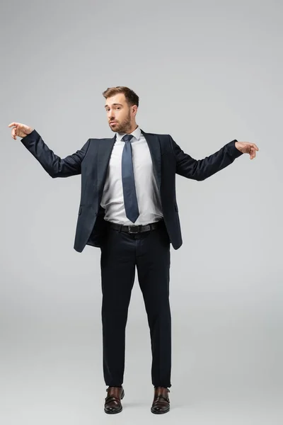 Бізнесмен маріонетка в костюмі позує з піднятими руками ізольовано на сірому — стокове фото