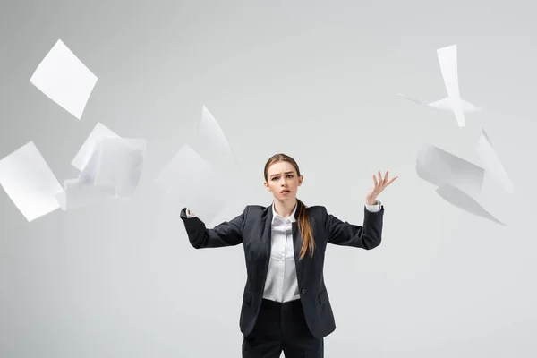 Displeased businesswoman in suit throwing papers in air isolated on grey — Stock Photo