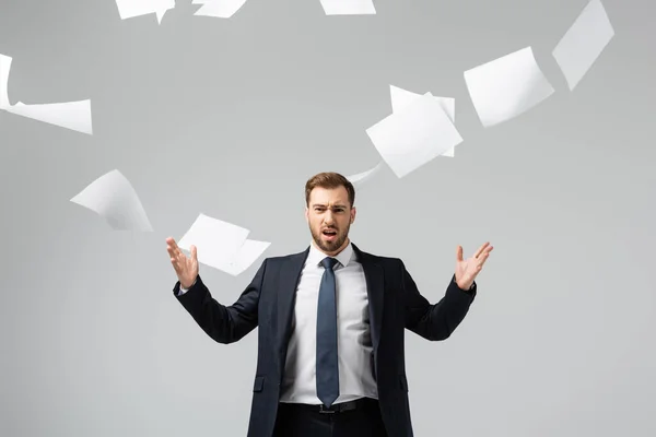 Displeased businessman in suit throwing papers in air isolated on grey — Stock Photo