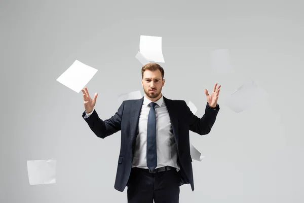 Displeased businessman in suit throwing papers in air isolated on grey — Stock Photo