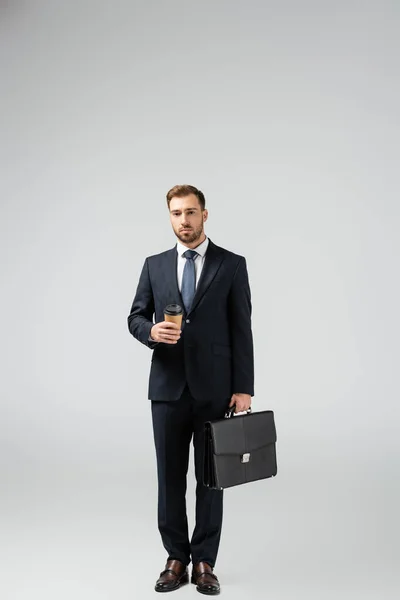 Uomo d'affari con valigia in pelle e bicchiere di carta isolato su grigio — Foto stock