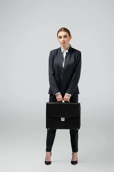 Young businesswoman with leather suitcase isolated on grey — Stock Photo