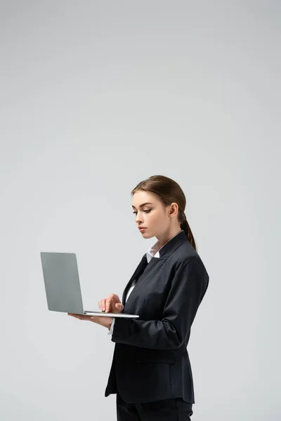 Ernsthafte junge Geschäftsfrau mit Laptop isoliert auf grau — Stockfoto