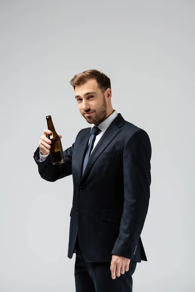 Hombre de negocios guapo en traje con cerveza aislada en gris - foto de stock