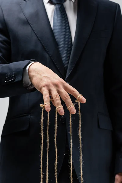 Partial view of puppeteer in suit with strings on fingers — Stock Photo