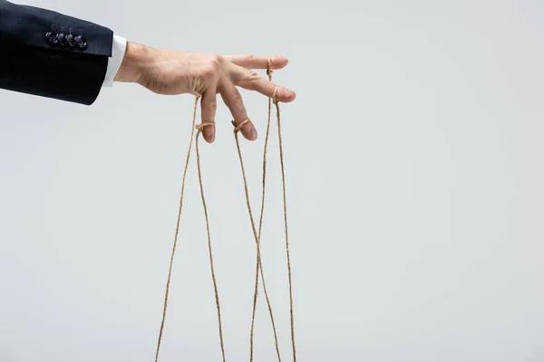 Partial view of puppeteer with strings on fingers isolated on grey — Stock Photo