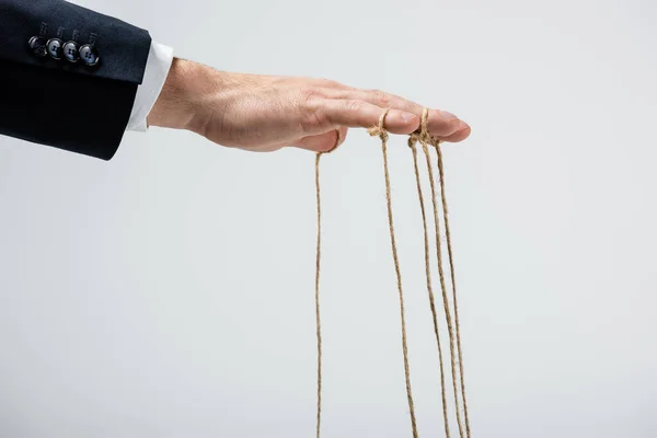 Partial view of puppeteer with strings on fingers isolated on grey — Stock Photo