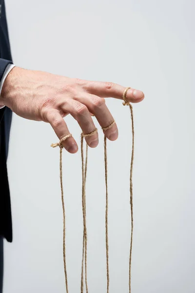 Partial view of puppeteer with strings on fingers isolated on grey — Stock Photo