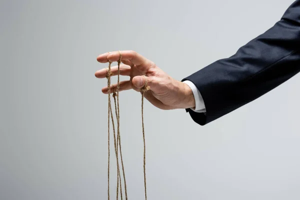 Cropped view of puppeteer with strings on fingers isolated on grey — Stock Photo