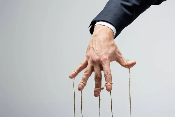 Cropped view of puppeteer with strings on fingers isolated on grey — Stock Photo