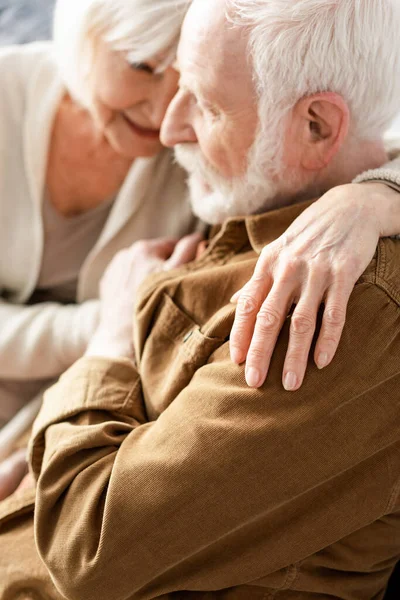Foco seletivo de sorrir mulher idosa abraçando marido atencioso — Fotografia de Stock