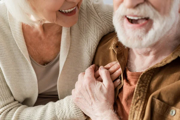 Vista recortada de la risa pareja de ancianos cogidos de la mano, enfoque selectivo - foto de stock