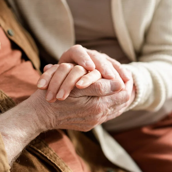 Обрезанный вид пожилой пары, держащейся за руки, избирательный фокус — стоковое фото