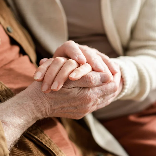 Recortado vista de la pareja de personas mayores cogidas de la mano, enfoque selectivo - foto de stock