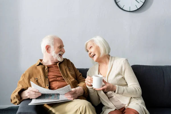 Щаслива старша пара говорить, сидячи на дивані вдома — стокове фото