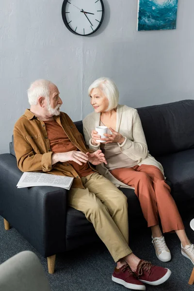 Высокий угол обзора пожилой пары, разговаривающей, сидя на диване — стоковое фото