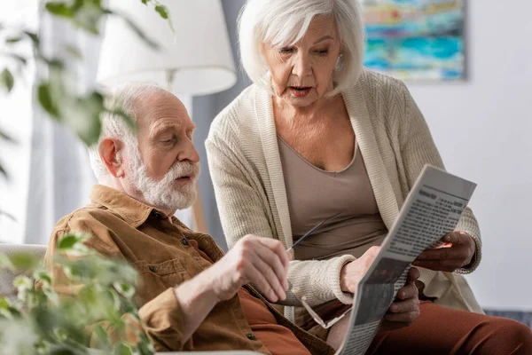 Selective focus of attentive senior couple reading newspaper together — Stock Photo