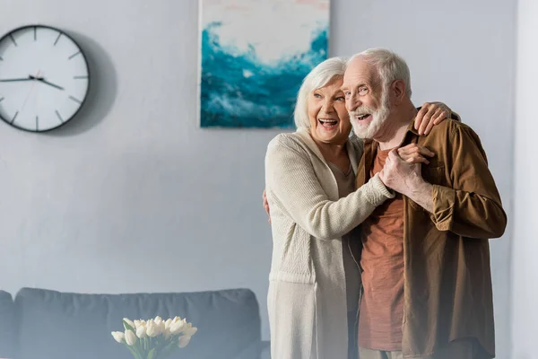 Happy senior couple dancing at home and looking away — Stock Photo