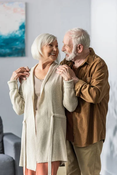 Щасливий старший чоловік торкається плечей веселої дружини, дивлячись один на одного — стокове фото