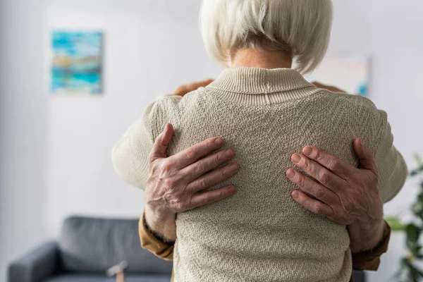 Rückansicht einer Seniorin, die von ihrem Mann umarmt wird — Stockfoto