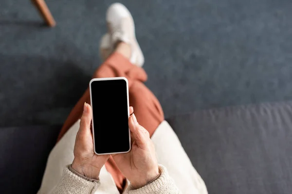 Vista superior da mulher sênior sentado e segurando smartphone com tela em branco — Fotografia de Stock