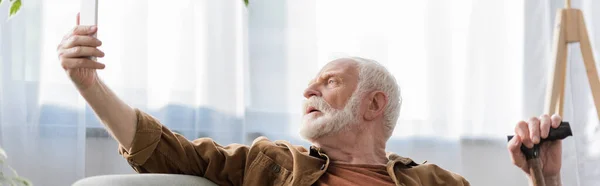 Horizontal image of senior man taking selfie on smartphone — Stock Photo