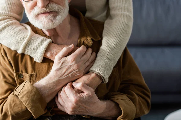 Обрізаний вид жінки, що обіймає старшого чоловіка і тримає його за руки — стокове фото