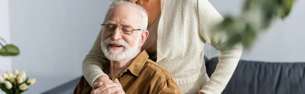 Cropped view of woman embracing happy senior husband, panoramic crop — Stock Photo