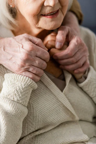 Обрізаний вид на старшого чоловіка, тримаючи руки усміхненої дружини — стокове фото