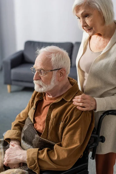 Despaired senior woman touching shouder of disabled husband, sick on dementia — Stock Photo