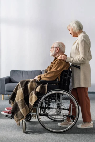 Side view of senior woman touching shoulder of handicapped husband, sick on dementia — Stock Photo