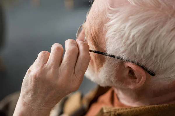 Blick von oben auf alleinstehenden Senior, der Brille berührt — Stockfoto