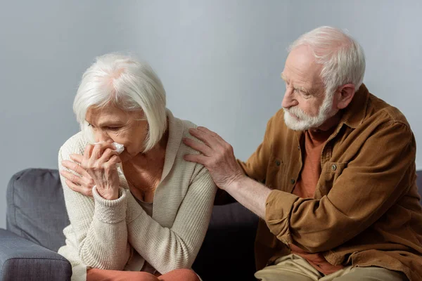 Senior man calming crying wife while touching her shoulder — Stock Photo