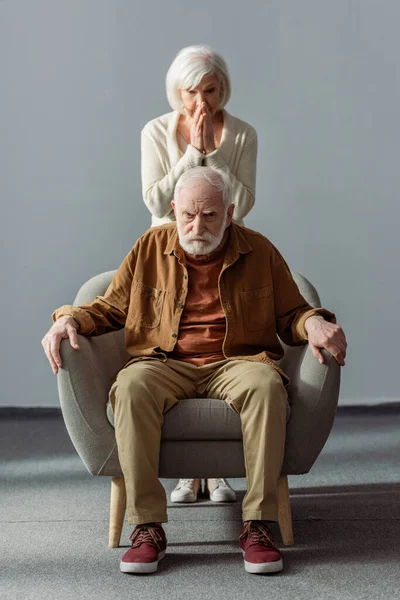 Shocked senior woman touching face while standing behind husband, sick on dementia — Stock Photo