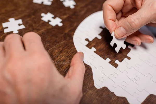 Cropped view of sick senior man combining jigsaw puzzle for dementia therapy — Stock Photo